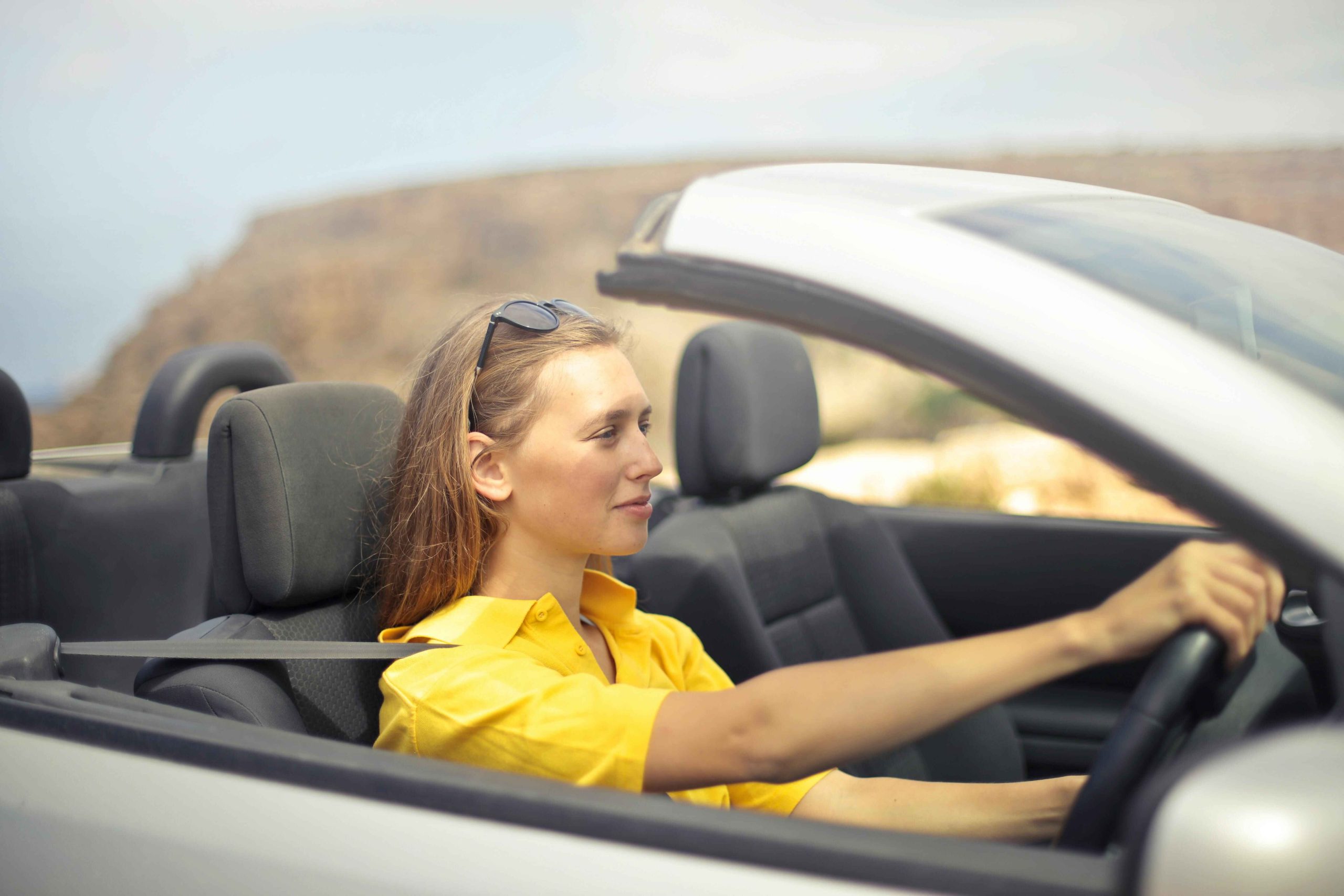 Woman wearing a yellow shirt driving a silver car. How do car loans work?
